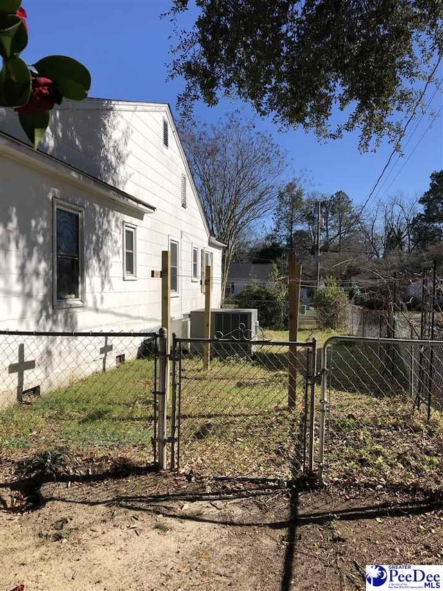 view of side of home featuring a gate, fence, crawl space, and central AC unit