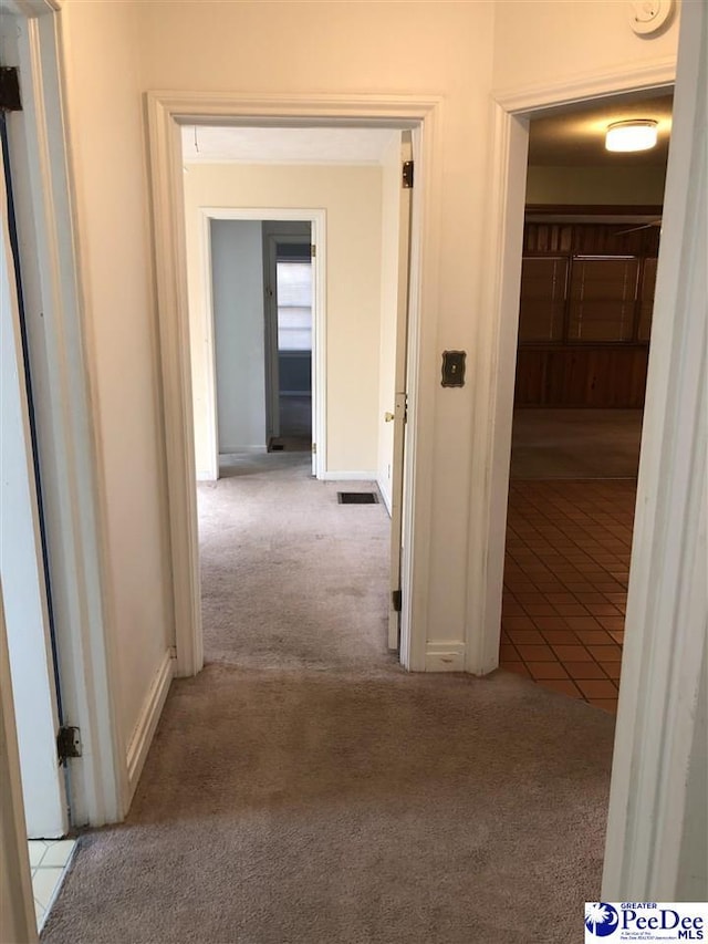 hallway featuring carpet flooring, visible vents, and baseboards