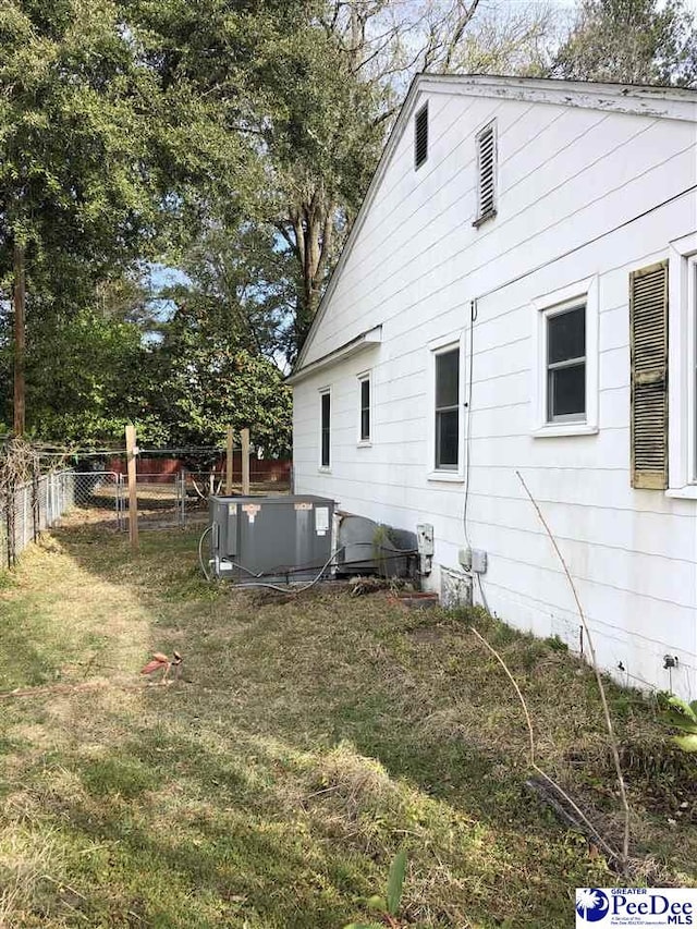 view of property exterior with central AC unit, a lawn, and a fenced backyard