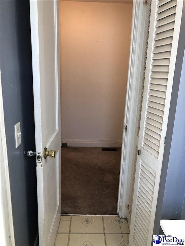 corridor featuring light carpet, visible vents, and baseboards