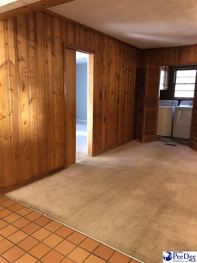 interior space with wood walls, washing machine and dryer, and light colored carpet