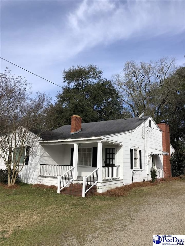 view of front of property featuring a porch, a chimney, and a front lawn