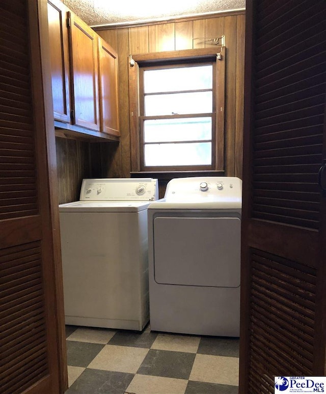 laundry area featuring cabinet space, separate washer and dryer, light floors, and wood walls