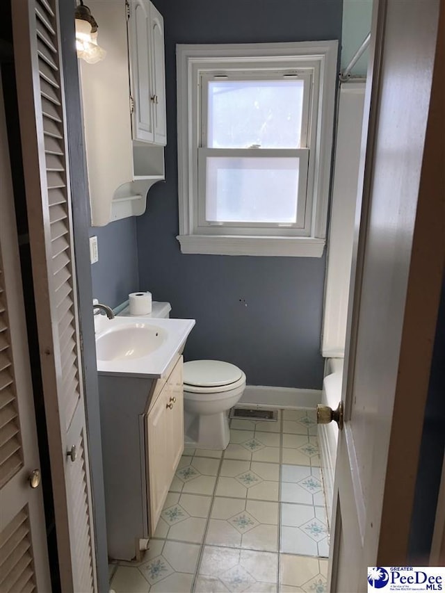 bathroom with visible vents, toilet, vanity, baseboards, and tile patterned floors