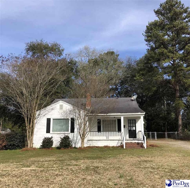 view of front of house with covered porch, fence, and a front lawn