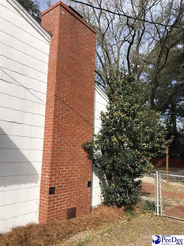 view of home's exterior with crawl space, fence, and a chimney