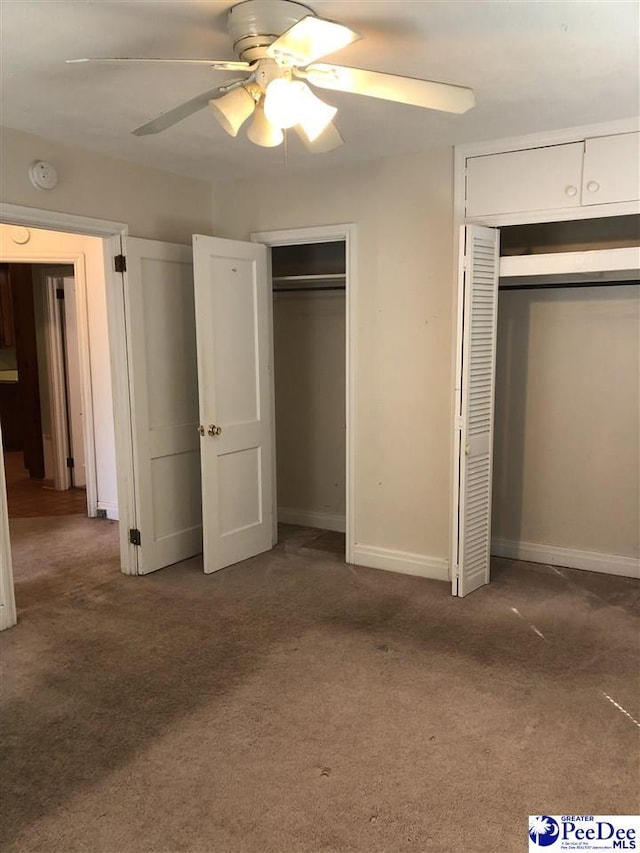 unfurnished bedroom with ceiling fan, carpet, two closets, and baseboards