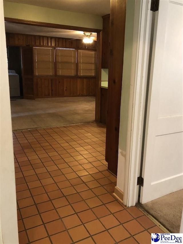 hall featuring wooden walls, washer / clothes dryer, and light colored carpet