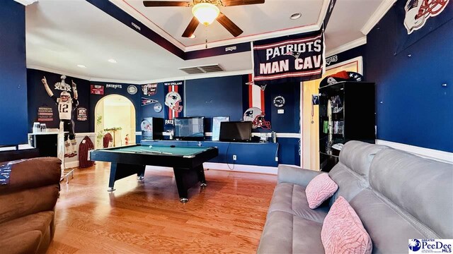 recreation room featuring hardwood / wood-style flooring, pool table, ceiling fan, a raised ceiling, and crown molding