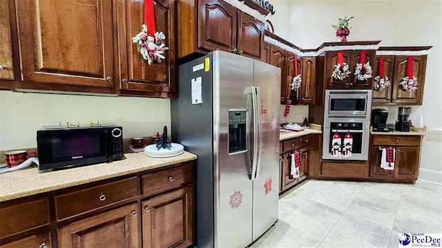 kitchen with stainless steel appliances, light tile patterned flooring, and dark brown cabinets
