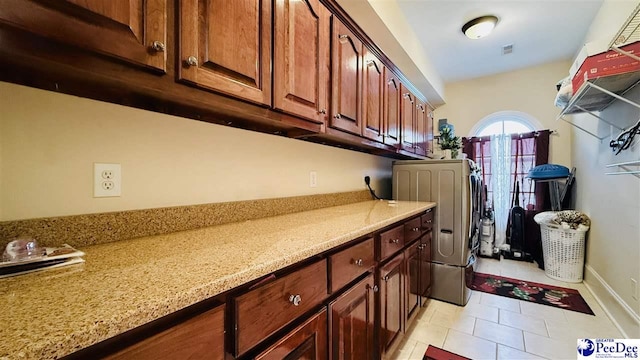 clothes washing area featuring hookup for an electric dryer, cabinets, and light tile patterned flooring