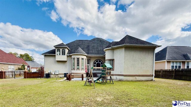 back of property with a lawn and a playground