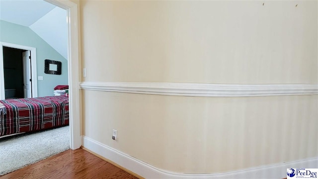 hallway with lofted ceiling and hardwood / wood-style floors