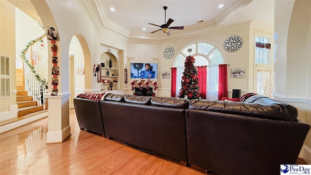 living room featuring ornate columns, ornamental molding, ceiling fan, light hardwood / wood-style floors, and built in shelves