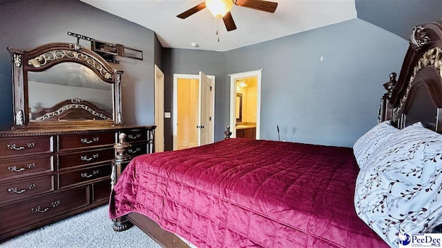 bedroom with ceiling fan, light colored carpet, vaulted ceiling, and ensuite bath