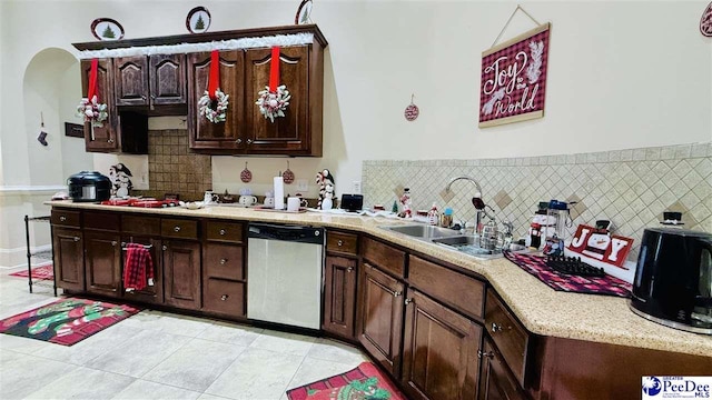 kitchen featuring dark brown cabinetry, sink, tasteful backsplash, light tile patterned floors, and dishwasher