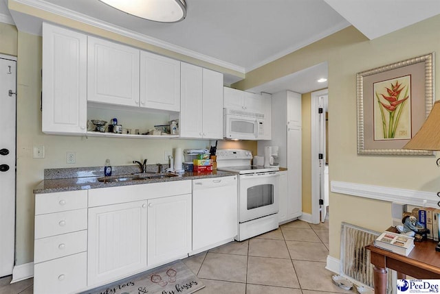 kitchen featuring white appliances, white cabinetry, a sink, dark stone countertops, and light tile patterned floors