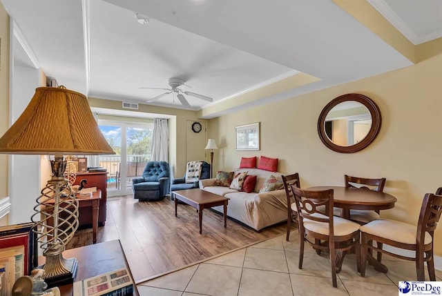 living area featuring crown molding, a ceiling fan, visible vents, and light tile patterned floors