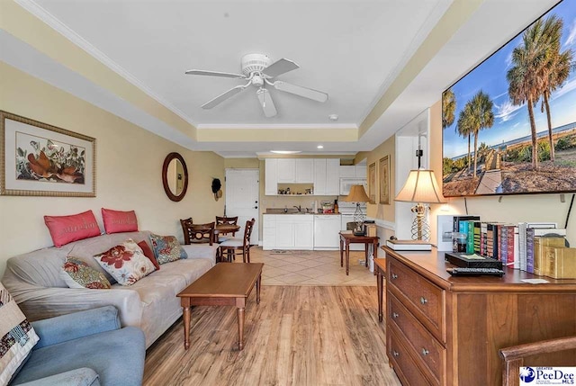 living room with ceiling fan, ornamental molding, a tray ceiling, and light wood finished floors
