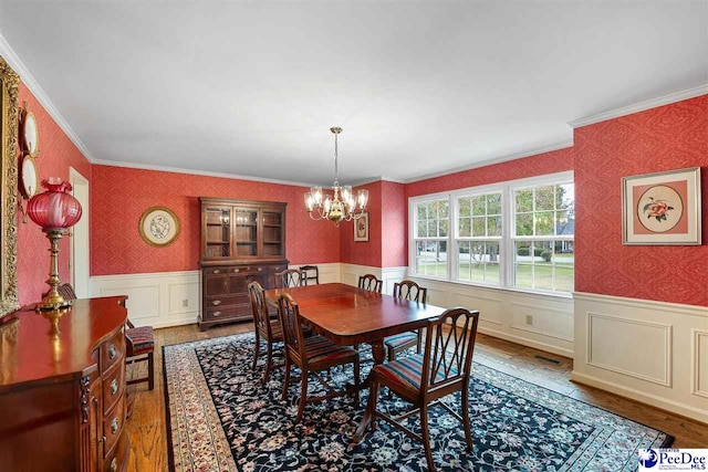 dining room with hardwood / wood-style floors, crown molding, and a chandelier