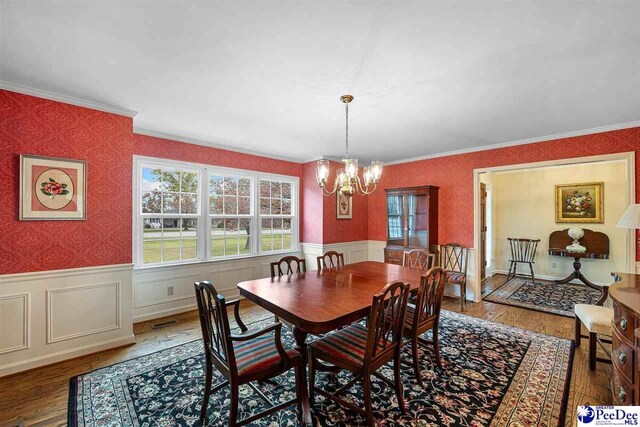 dining space with an inviting chandelier, crown molding, and dark hardwood / wood-style floors