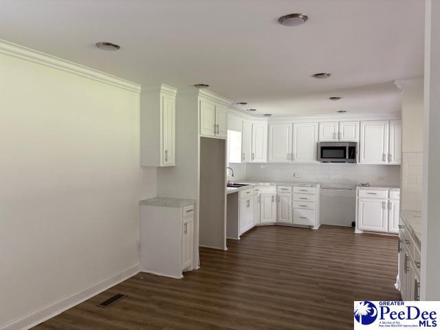 507 Arbor Dr, Florence, SC 29501 - kitchen with stainless steel microwave, a sink, dark wood finished floors, decorative backsplash, and crown molding