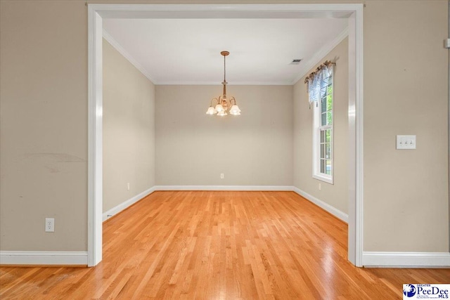 spare room featuring light wood-type flooring, ornamental molding, baseboards, and a notable chandelier