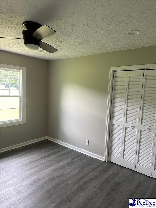 unfurnished bedroom with ceiling fan, dark hardwood / wood-style floors, a closet, and a textured ceiling