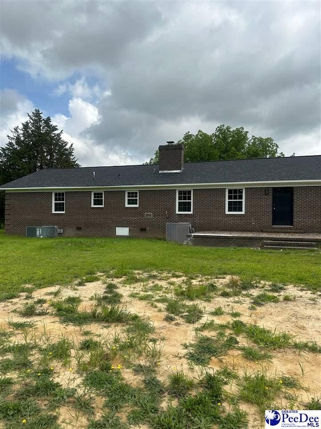 back of property with a yard and central AC unit