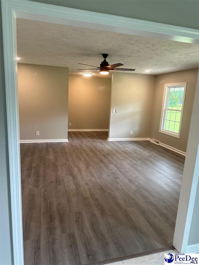 unfurnished room featuring ceiling fan, dark hardwood / wood-style flooring, and a textured ceiling