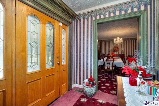 carpeted foyer entrance with a chandelier and a textured ceiling