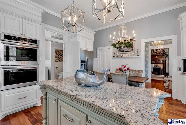 kitchen featuring ornamental molding, appliances with stainless steel finishes, dark hardwood / wood-style flooring, and decorative light fixtures