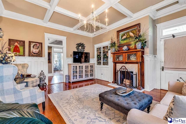 living room with hardwood / wood-style flooring, coffered ceiling, an inviting chandelier, and beam ceiling