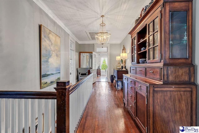 hall with an inviting chandelier, crown molding, and dark wood-type flooring