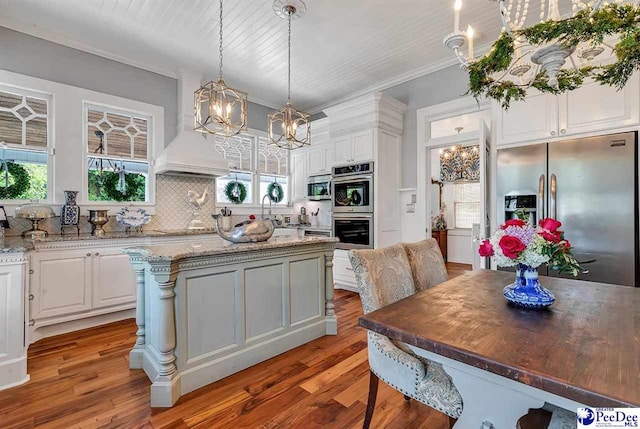 kitchen with stainless steel appliances, white cabinetry, hanging light fixtures, and a center island