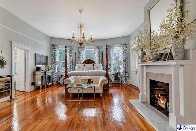 bedroom featuring wood-type flooring, a premium fireplace, and a chandelier