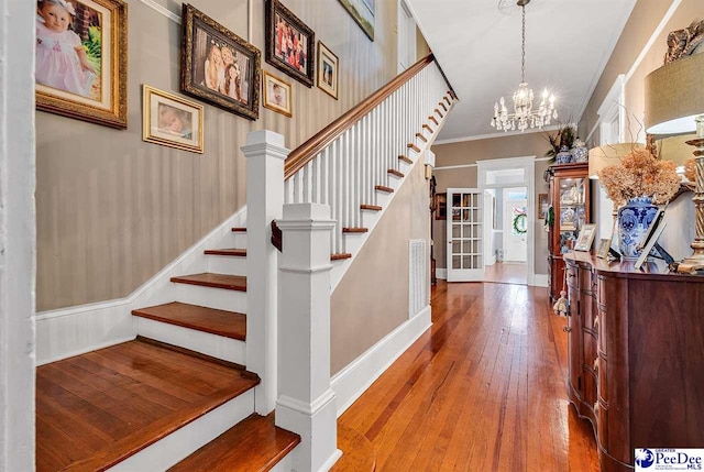 stairway featuring ornamental molding, hardwood / wood-style floors, and a notable chandelier