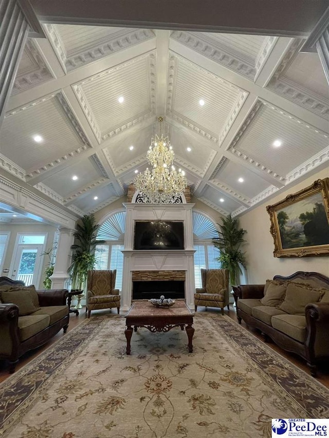 living room with coffered ceiling, a stone fireplace, wood-type flooring, a chandelier, and lofted ceiling with beams