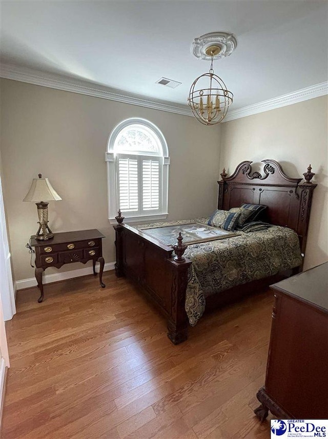 bedroom featuring an inviting chandelier, ornamental molding, and light hardwood / wood-style floors