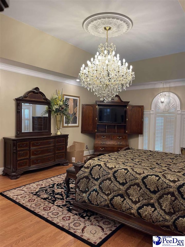 bedroom featuring crown molding, a tray ceiling, hardwood / wood-style floors, and a notable chandelier