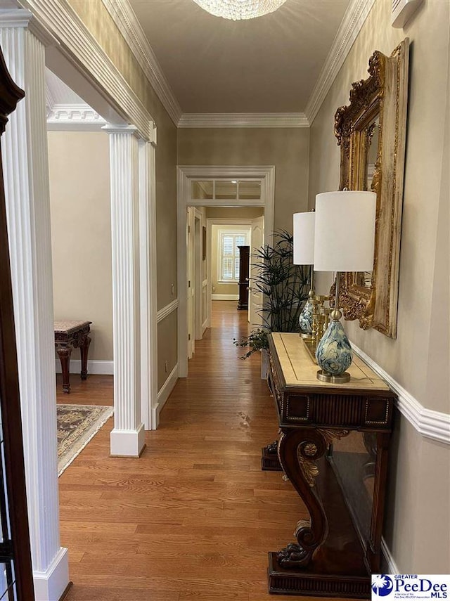 hallway featuring ornate columns, ornamental molding, and light hardwood / wood-style flooring