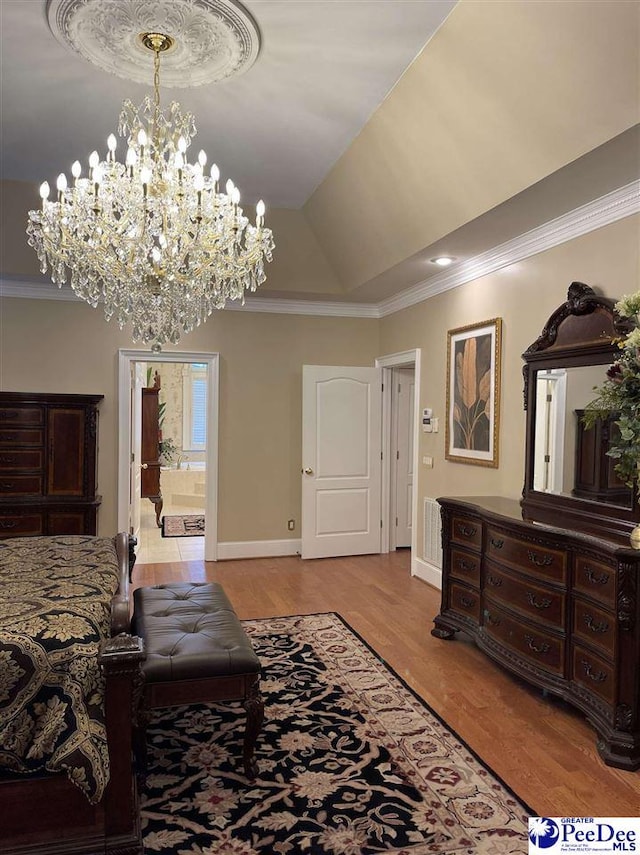 bedroom with connected bathroom, crown molding, vaulted ceiling, light hardwood / wood-style flooring, and a tray ceiling