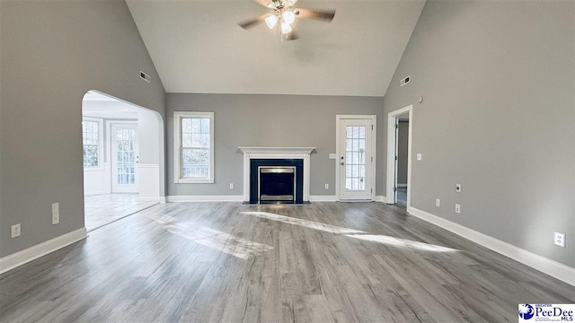 unfurnished living room featuring wood-type flooring, high vaulted ceiling, and ceiling fan