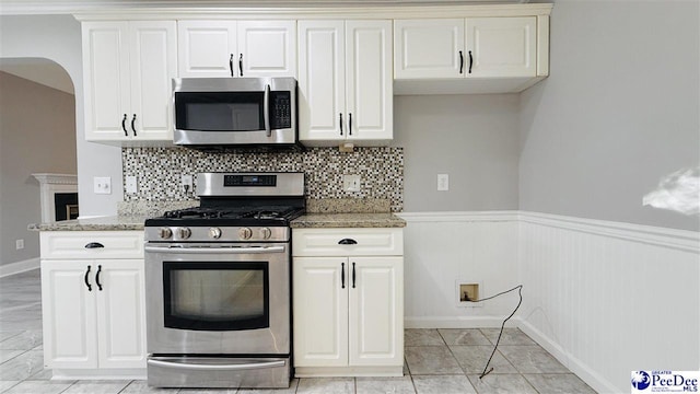 kitchen with white cabinetry, appliances with stainless steel finishes, light stone countertops, and decorative backsplash