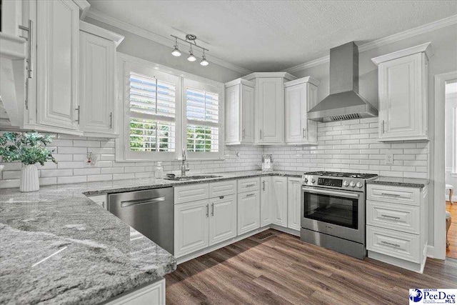 100 Mckellar St, Bennettsville, SC 29512 - kitchen with appliances with stainless steel finishes, wall chimney range hood, a sink, white cabinetry, and ornamental molding