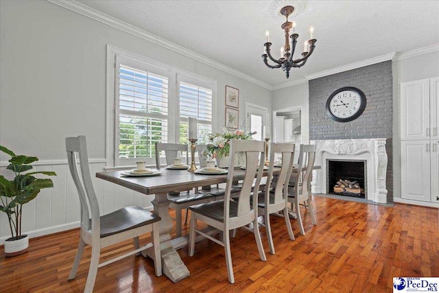 100 Mckellar St, Bennettsville, SC 29512 - dining room featuring a chandelier, light wood-type flooring, a fireplace, crown molding, and a wainscoted wall