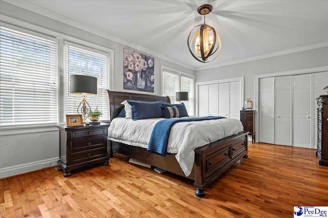 100 Mckellar St, Bennettsville, SC 29512 - bedroom with light wood-style flooring, multiple closets, ornamental molding, baseboards, and a chandelier