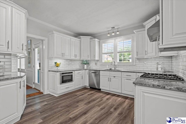 100 Mckellar St, Bennettsville, SC 29512 - kitchen featuring stainless steel appliances, wall chimney exhaust hood, a sink, white cabinetry, and ornamental molding