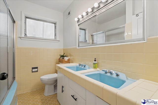 bathroom with tile patterned floors, vanity, toilet, and tile walls