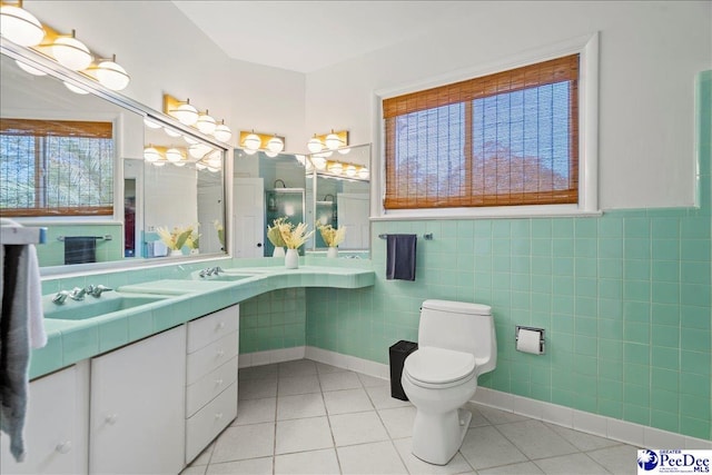 bathroom featuring vanity, toilet, tile patterned flooring, and tile walls